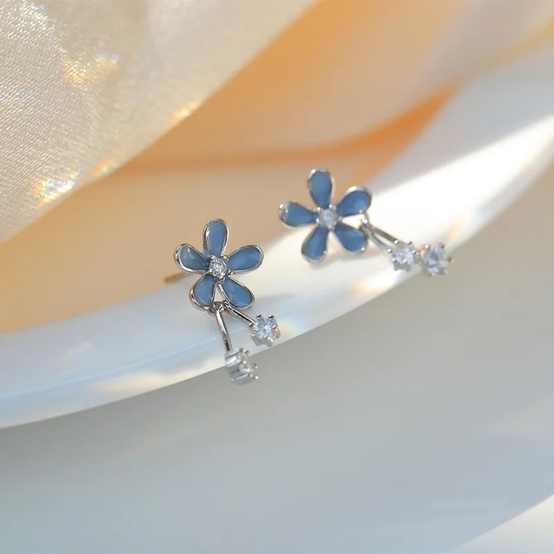 Floral earrings with blue flowers and clear stones on a soft background