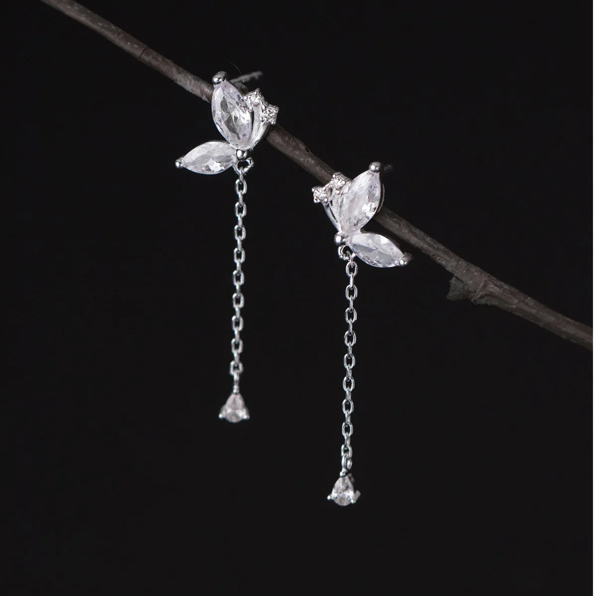Silver earrings with floral designs on a dark background